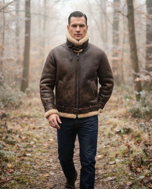 A man wearing a brown leather aviator jacket with beige shearling lining, walking on a forest path during foggy autumn.