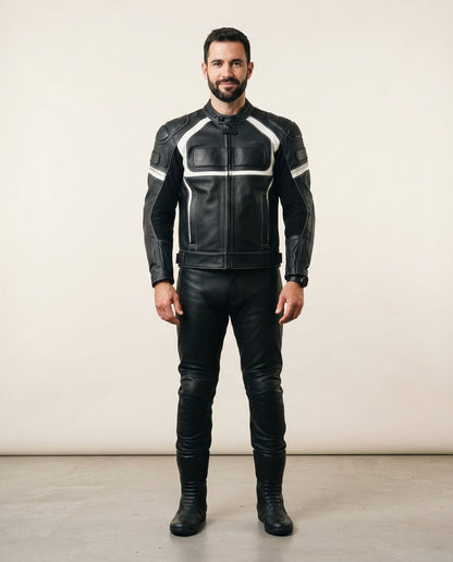 A man wearing a black leather motorcycle jacket with white contrast stitching and matching black leather pants and boots, standing against a plain beige studio background.
