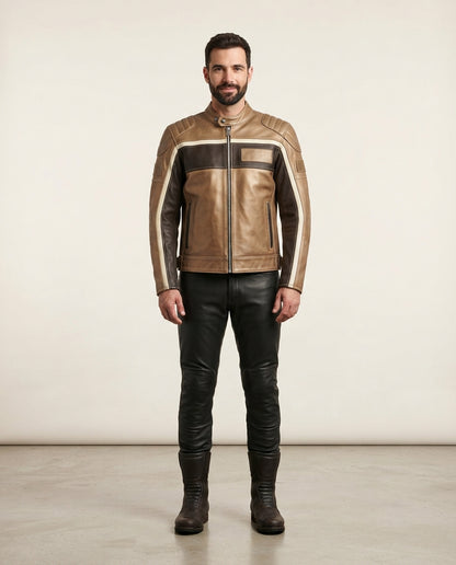 A man stands facing forward wearing a tan and dark brown leather jacket with contrasting light beige stripes on the sleeves, paired with black leather pants and dark brown boots, against a plain light beige studio background.